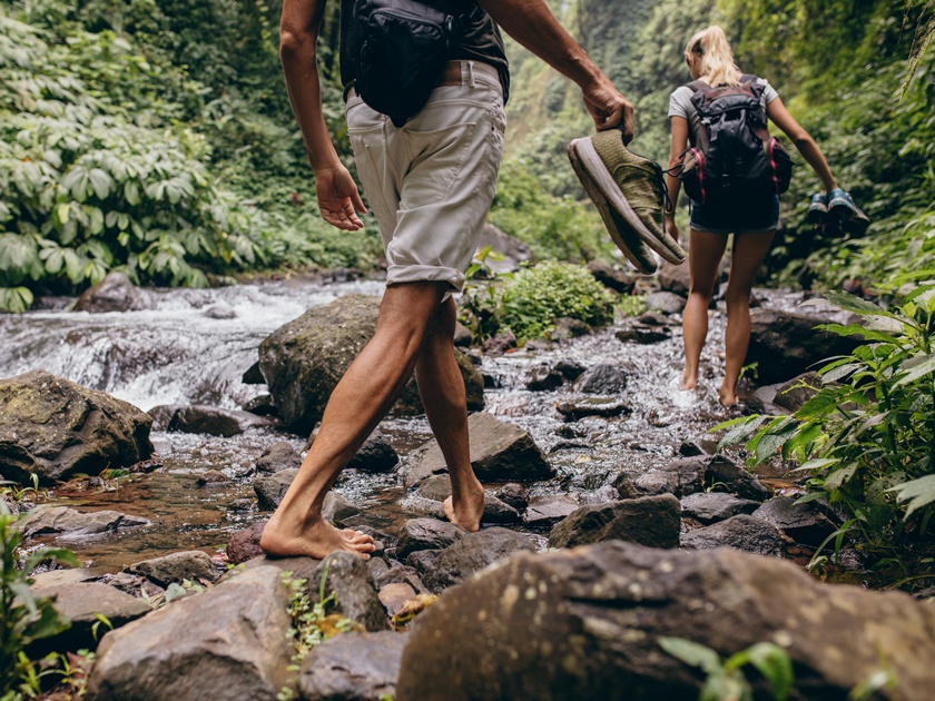 Low,Section,Shot,Of,Man,And,Woman,Crossing,The,Stream