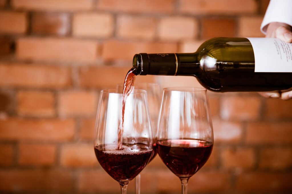 ワイングラスに赤ワインを注ぐ人の手