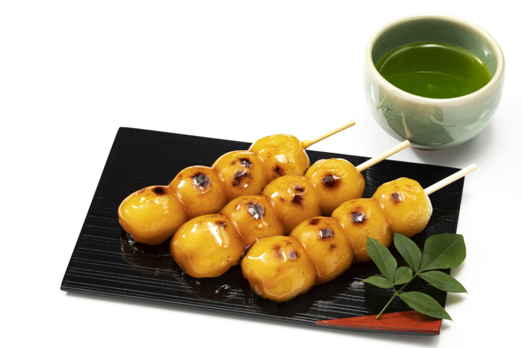 黒い角皿に並ぶ3本のみたらし団子と日本茶