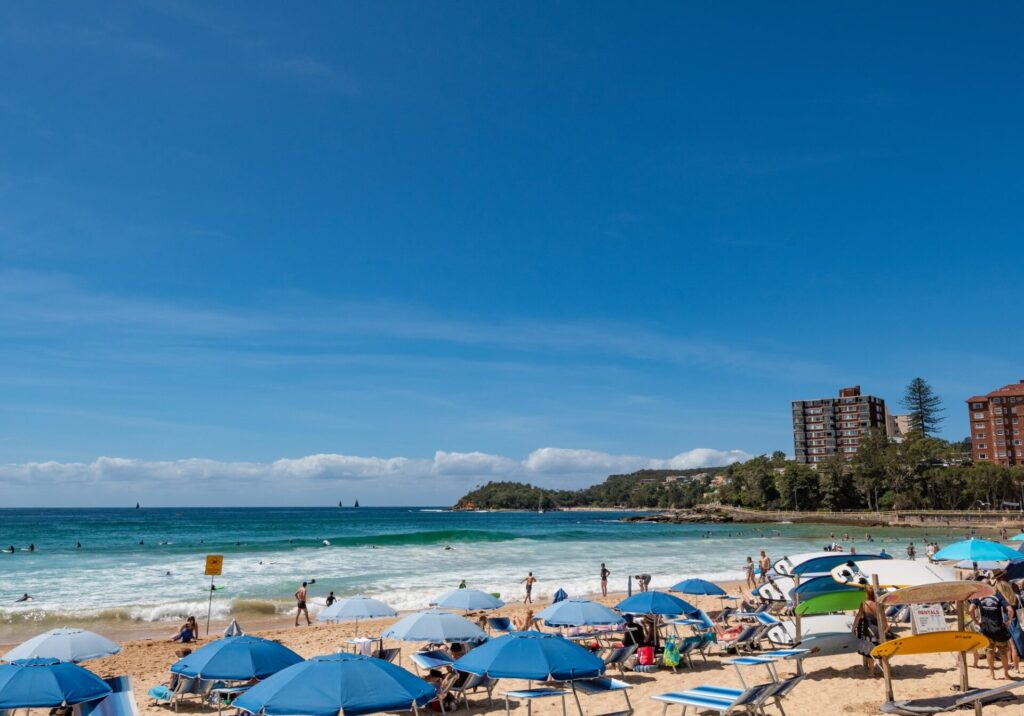 シドニー　のマンリー・ビーチを楽しむ人とパラソル