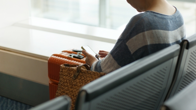 空港のゲートでスーツケースを持って待つ人