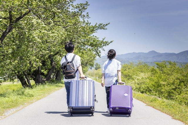 観光地をキャリーケースを引きながら歩く男女
