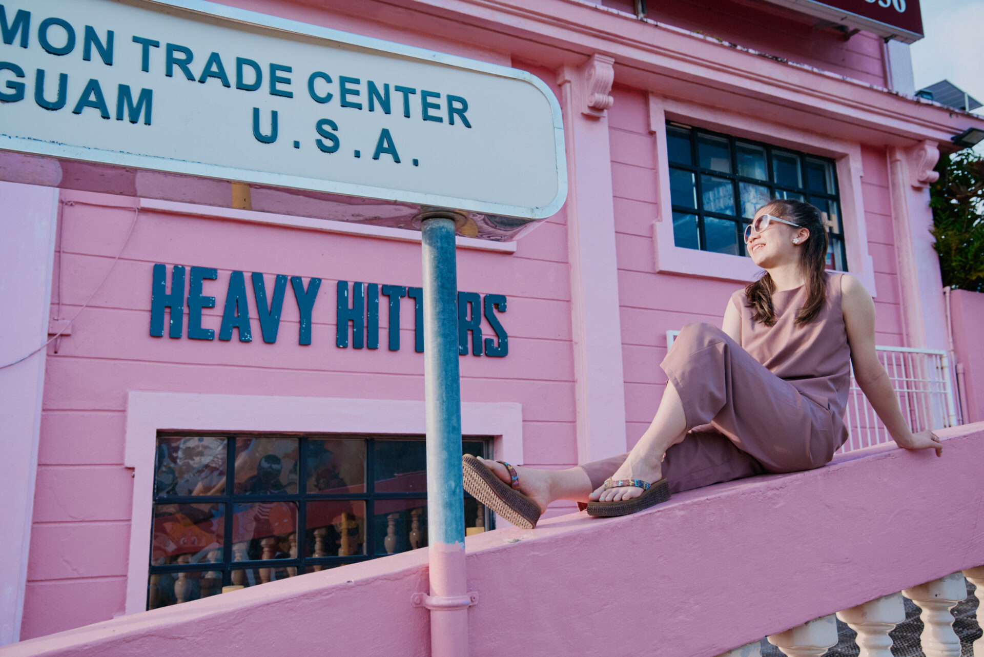 日本から近い海外・グアムで訪れたい、タモントレードセンタービルの「ピンクの建物」前でポーズをとる女性