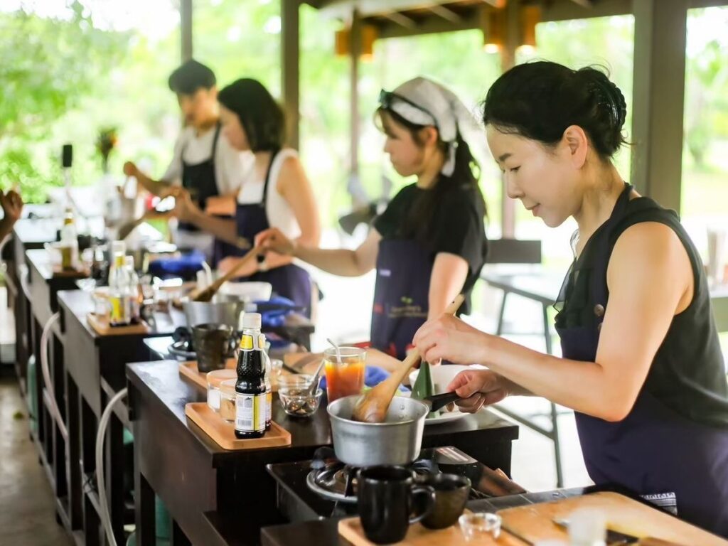 タイのウェルネスツーリズムで体験したい、チェンマイにある自然に囲まれた料理教室で料理をする様子